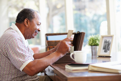 A senior man reads an old letter taken from a wooden box.