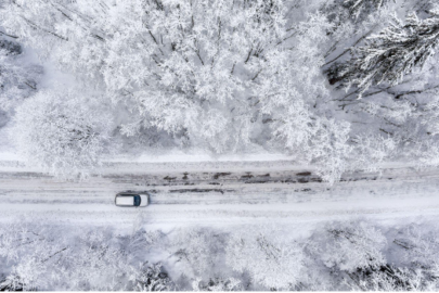 One vehicle driving through the winter snowy forest on a country road.
