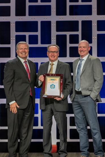 Three men holding an award.