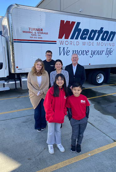 People smiling in front of a Wheaton truck.