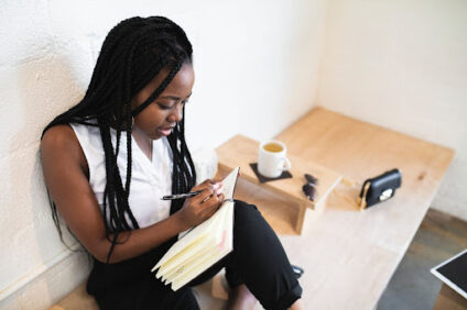 A woman sitting on a bench and writing in a journal.