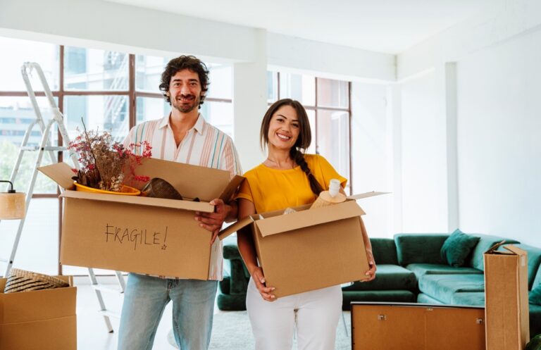 A young couple holds moving boxes in their new home.