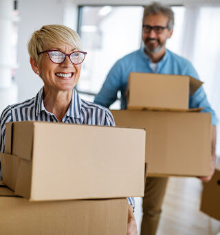 Two people moving boxes and smiling.