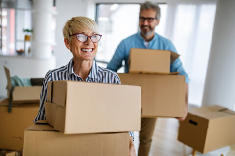 Two people moving boxes and smiling.