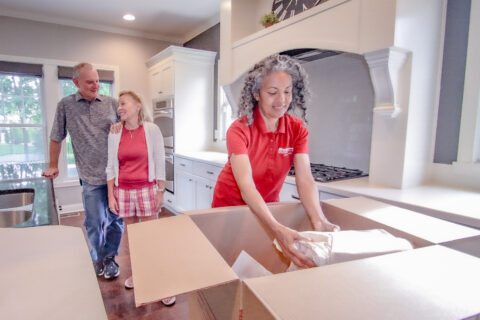 wheaton moving expert packing older adults' belongings into cardboard box.