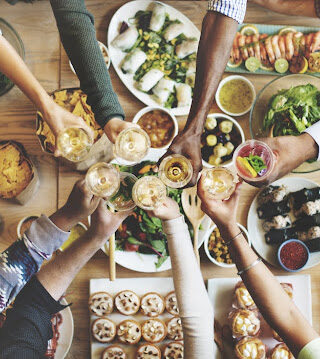 People toasting over a table full of food.