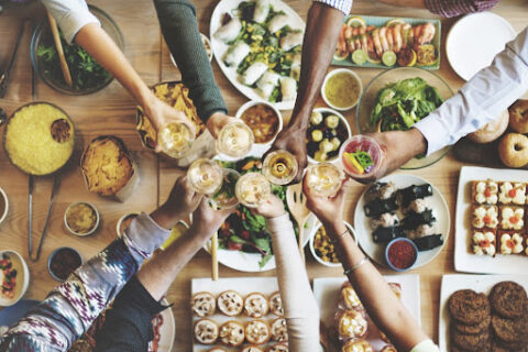 People toasting over a table full of food.