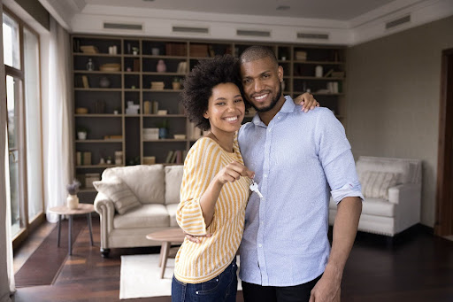 A couple holding keys and smiling.