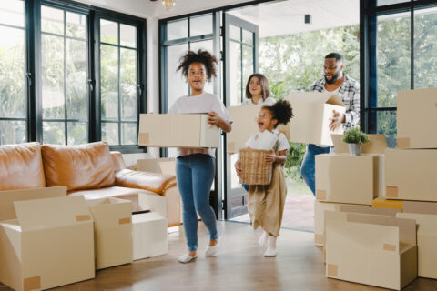 A family with two kids walks into a new home full of moving boxes.