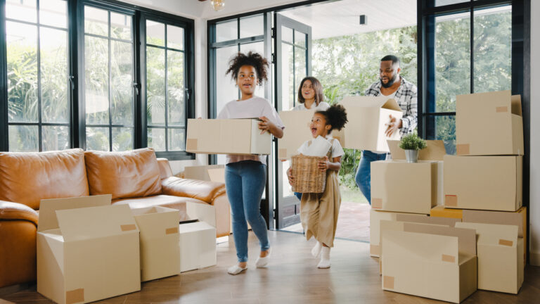 A family with two kids walks into a new home full of moving boxes.