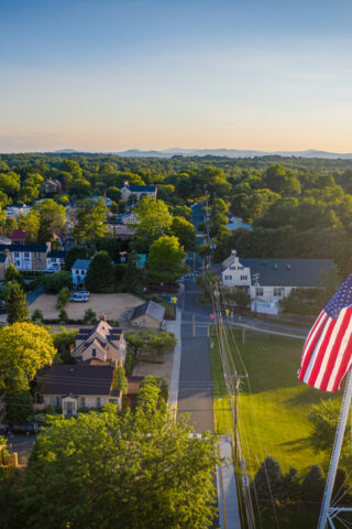 Birds-eye view of a rural town with a water tower and an American flag.
