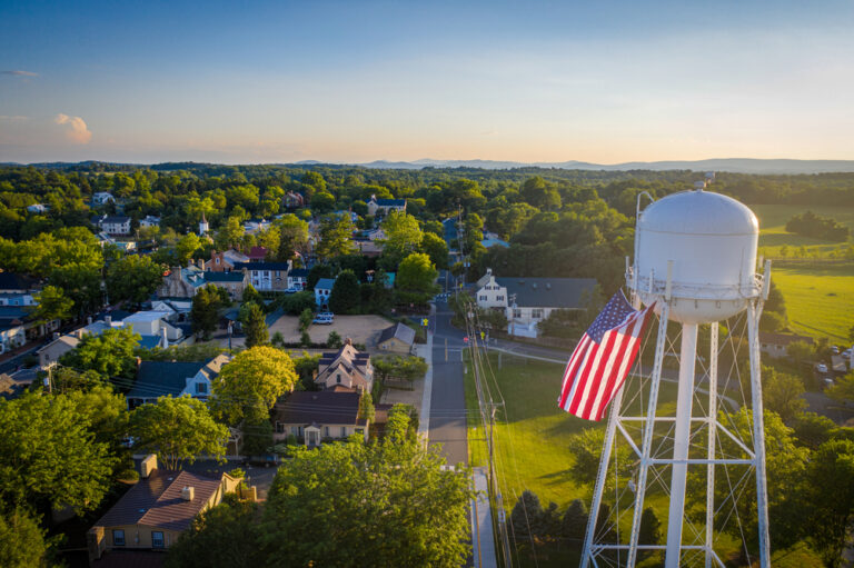 Birds-eye view of a rural town with a water tower and an American flag.